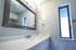 Modern bathroom with sleek vanity, large mirror, and natural light from a narrow window.