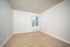 Inviting, minimalist room with soft beige carpet and a bright window filling the space with natural light.