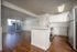 Chic open-concept apartment featuring elegant hardwood floors, a modern kitchen with sleek white cabinetry, and sliding glass doors leading to a private balcony.