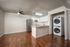Modern open-concept kitchen with sleek appliances, wood flooring, and a convenient in-unit washer and dryer setup.