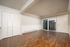 Spacious living area with elegant wood floors, large windows for ample natural light, and stylish white paneled walls.
