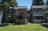 Charming two-story apartment building with lush greenery and a welcoming facade, perfect for tranquil living.