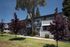 Charming two-story apartment building with modern gray facade, surrounded by lush landscaping and vibrant trees, offering a serene and inviting atmosphere.