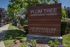 Inviting entrance sign for Plum Tree Apartment Homes surrounded by lush greenery and a welcoming sidewalk.