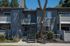 Charming apartment exterior with modern gray facade, private balconies, and lush greenery, featuring a welcoming staircase entrance.