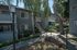 Charming apartment exterior with lush greenery and elegant stairway leading to a second-floor entrance under a clear sky.
