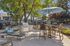 Inviting outdoor patio featuring a chic dining set under a large umbrella, modern grill, and comfortable lounge chairs amid lush landscaping.
