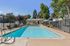 Inviting outdoor pool area with crystal-clear water, surrounded by lush greenery and modern amenities, perfect for relaxation and entertainment.
