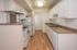 Bright and modern kitchen with elegant white cabinetry, sleek appliances, and warm wooden flooring, promising a welcoming cooking space.