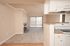 Bright and spacious living area with plush carpet, charming fireplace, and a modern kitchen with white cabinetry.