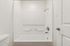 Pristine white bathroom showcasing a modern tub with sleek fixtures and elegant design.