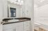 Bright and elegant bathroom with modern vanity, sleek countertop, and pristine bathtub, offering a relaxing retreat.