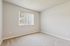 Bright and cozy bedroom with plush carpeting and a large window offering serene views.