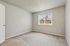 Bright and airy bedroom with plush carpet, elegant neutral walls, and a large window offering garden views.