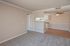 Inviting apartment interior showcasing a cozy living area with plush carpet, adjoining a sleek kitchen with modern cabinetry, and accented by warm wood flooring and a ceiling fan for comfort.