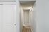 Bright and inviting hallway with elegant white sliding doors, leading to a cozy, carpeted interior space.