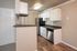 Modern kitchen with sleek stainless steel appliances, white cabinetry, and stylish wood flooring under warm lighting.