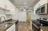 Modern kitchen with sleek stainless steel appliances, elegant white cabinetry, and wood-style flooring, perfect for a stylish home chef.