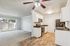 Bright and inviting open-plan living area featuring a modern kitchen with stainless steel appliances and elegant wooden flooring, leading to a cozy carpeted space and a large sliding glass door offering natural light.