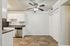 Modern kitchen with stainless steel appliances, elegant white cabinetry, and rich wood flooring, illuminated by a stylish ceiling fan.