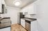 Contemporary kitchen with sleek stainless steel appliances, elegant white cabinetry, and warm wood flooring.