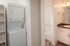 Modern apartment interior featuring a compact stacked washer and dryer beside a chic bathroom with elegant lighting.