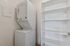 Compact laundry area with a modern stacked washer and dryer beside sleek white storage shelves, perfect for maximizing space in this stylish apartment.