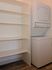 Modern apartment laundry area featuring a sleek stacked washer and dryer next to spacious open shelving.