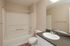 Modern bathroom featuring a sleek vanity with a polished sink, spacious mirror, and a full bathtub in a neutral-toned setting.