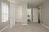 Bright and spacious bedroom with cozy carpet, featuring a walk-in closet and a connected modern bathroom, perfect for stylish living.