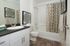 Modern bathroom featuring chic decor, elegant wood flooring, stylish vanity, and geometric patterned shower curtain.