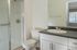 Bright and modern bathroom featuring a sleek shower, elegant countertop, and large mirror.