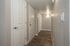 Inviting apartment entryway featuring elegant wooden flooring, modern lighting, and stylish white doors.