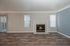 Spacious and inviting living room with elegant hardwood flooring, featuring a classic fireplace and abundant natural light.