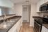 Modern kitchen with sleek countertops, stainless steel sink, and contemporary appliances, featuring a bright open design and wood flooring.