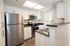 Modern kitchen with stainless steel appliances, bright white cabinets, and sleek countertops in a stylish apartment.