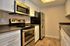 Modern kitchen with sleek stainless steel appliances, white cabinetry, and stylish wood flooring.