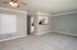 Bright and inviting living space with plush carpeting and modern ceiling fan, leading to a stylish open kitchen with stainless steel appliances.