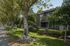 Charming residential building with lush greenery and spacious balconies surrounded by mature trees, offering serene suburban living.