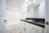 Bright modern bathroom featuring elegant black granite countertops, sleek white cabinetry, and a spacious bathtub.