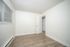 Bright minimalist room with sleek wooden flooring and modern white walls, perfect for personalization and creativity.