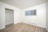 Bright and inviting bedroom with modern laminate flooring, spacious closet, and large window for natural light.