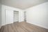 Bright and airy apartment bedroom with modern light wood flooring and ample closet space.