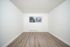Bright and airy minimalistic room with sleek wooden flooring and a large window, perfect for creative customization.