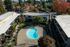 Charming aerial view of a serene apartment complex featuring a sleek kidney-shaped swimming pool surrounded by lush greenery and vibrant autumn foliage.