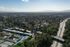 Scenic aerial view of a vibrant neighborhood with lush green spaces, tree-lined streets, and a picturesque swimming pool, offering a serene suburban lifestyle.