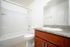 Modern bathroom featuring a sleek white bathtub, elegant granite countertop, and wooden cabinetry offering a touch of luxury.