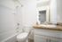 Modern bathroom showcasing a sleek granite countertop, stylish white fixtures, and elegant tiled shower area.