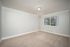 Bright, inviting room with soft beige carpeting, large window offering serene garden view, and elegant crown molding.