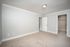 Bright and inviting bedroom with elegant crown molding, plush carpeting, and a spacious walk-in closet.